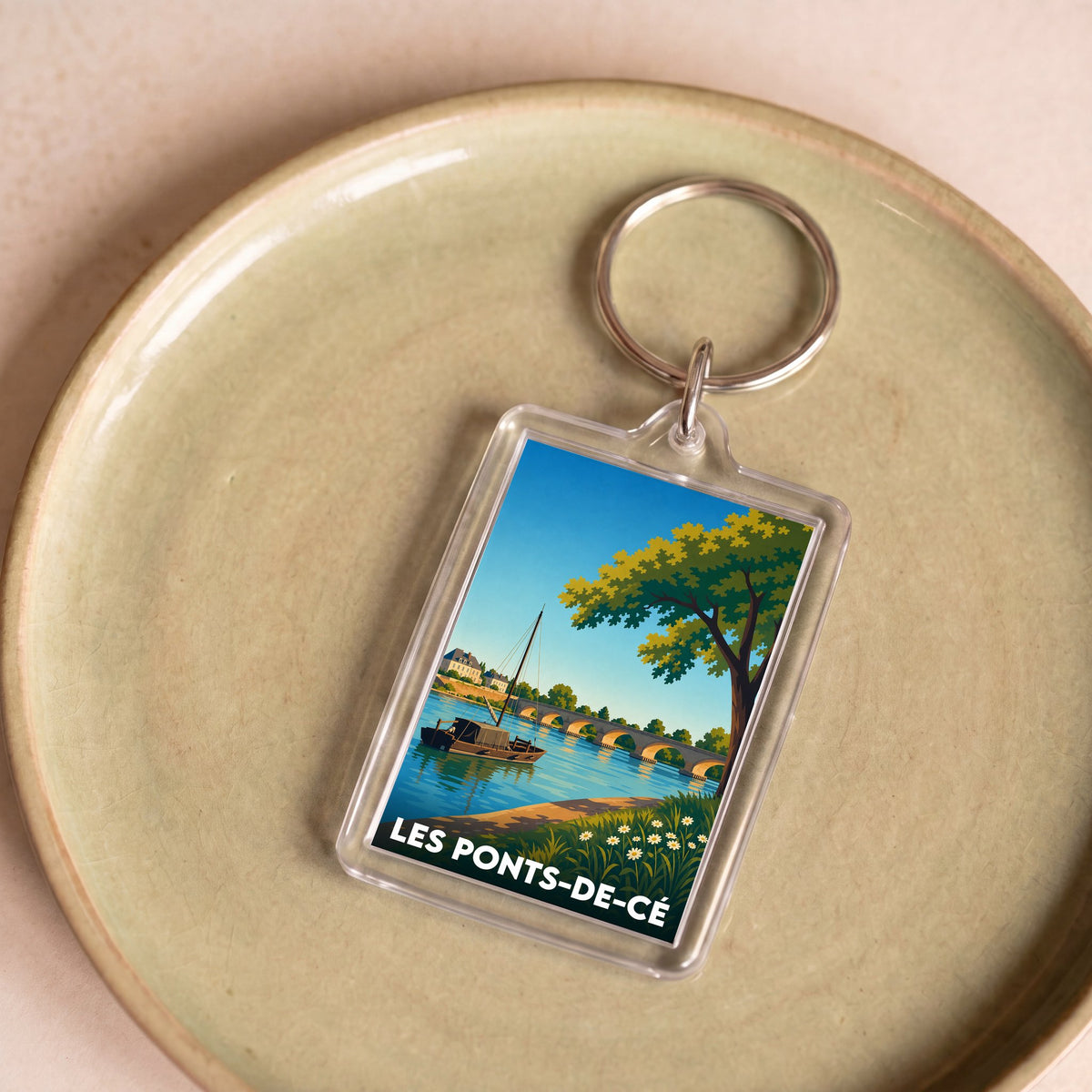 Porte-clés souvenir de la ville de Les Ponts-de-Cé avec une illustration stylisée d'un paysage de bord de Loire.