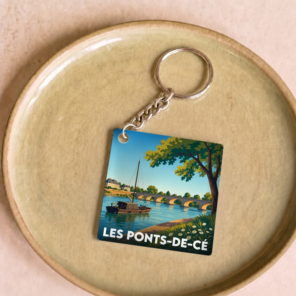 Porte-clés souvenir de la ville de Les Ponts-de-Cé avec une illustration stylisée d'un paysage de bord de Loire.
