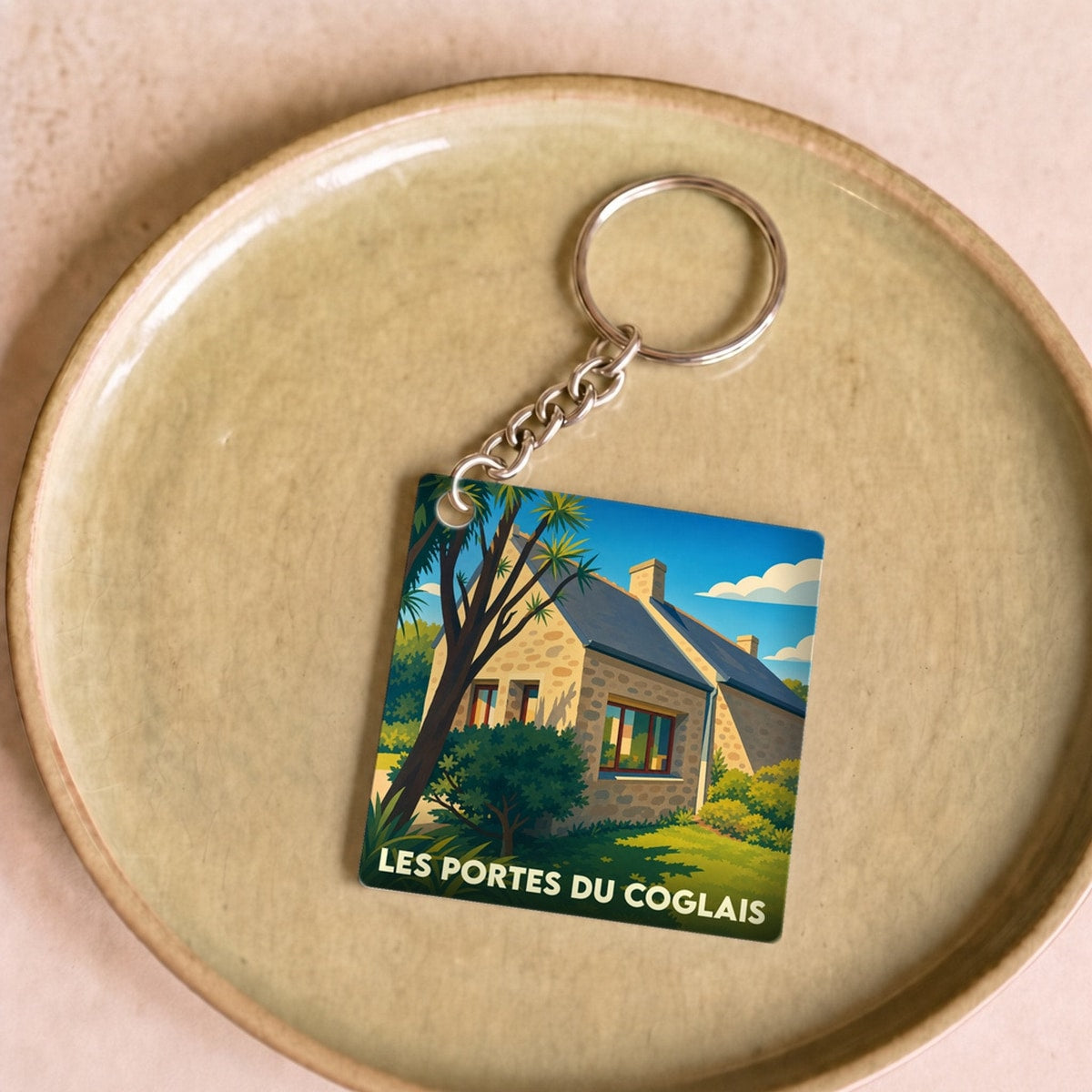 Porte-clés souvenir de la ville de Les Portes du Coglais avec une illustration stylisée.