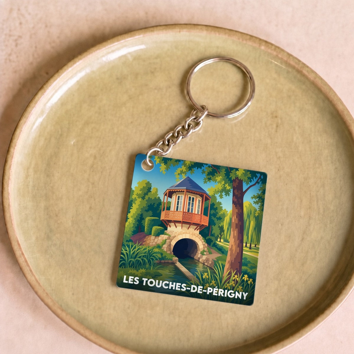 Porte-clés souvenir de la ville de Les Touches-de-Périgny avec une illustration stylisée d'un paysage local.