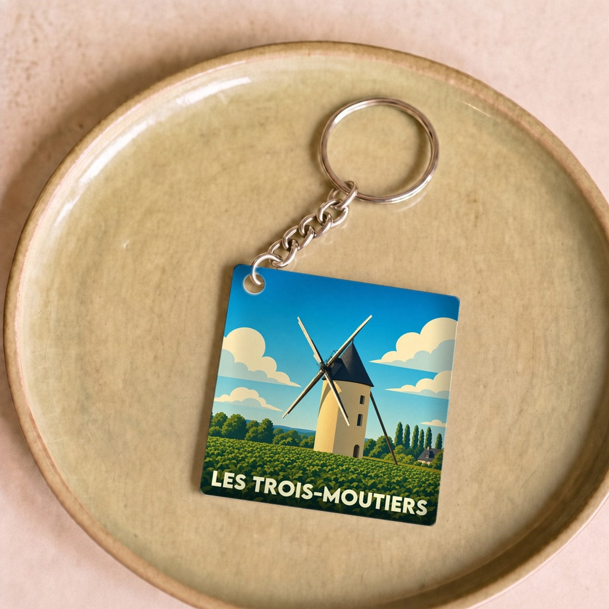 Porte-clés souvenir de la ville de Les Trois-Moutiers avec une illustration stylisée d'un moulin.
