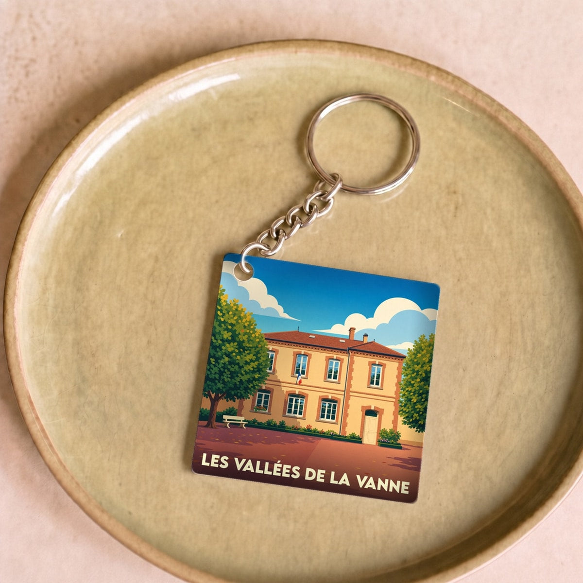 Porte-clés souvenir de la ville de Les Vallées de la Vanne avec une illustration stylisée d'un bâtiment historique.