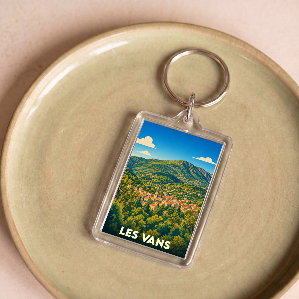Porte-clés souvenir de la ville de Les Vans avec une illustration stylisée d'un paysage montagneux.