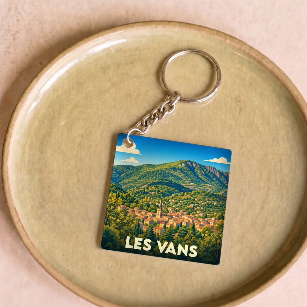 Porte-clés souvenir de la ville de Les Vans avec une illustration stylisée d'un paysage montagneux.