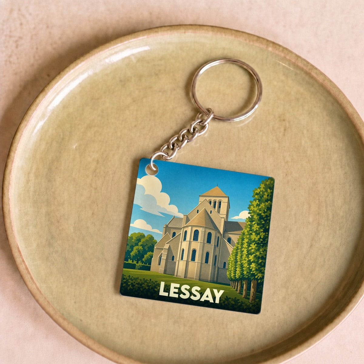 Porte-clés souvenir de la ville de Lessay illustrant son abbaye dans un style graphique épuré.