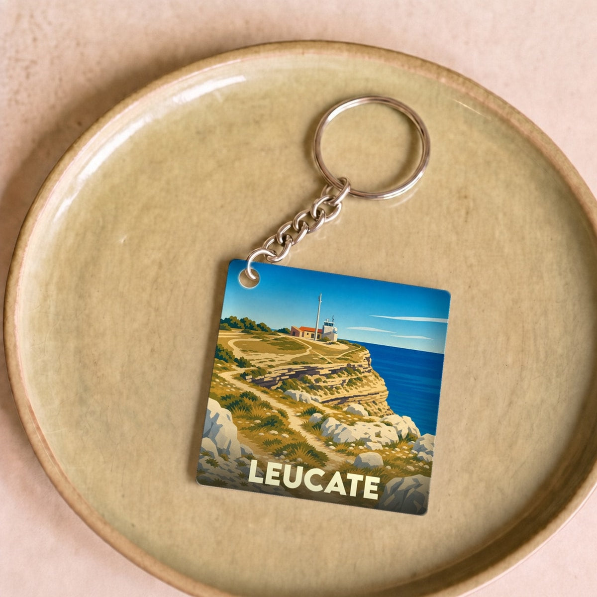 Porte-clés souvenir de la ville de Leucate avec une illustration stylisée de son phare et de ses falaises.