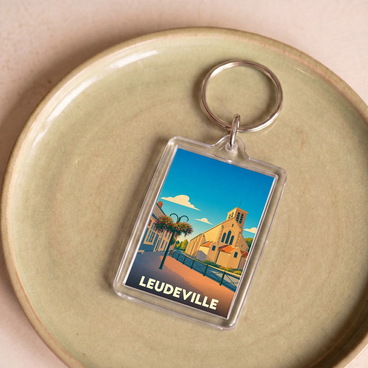 Porte-clés souvenir de la ville de Leudeville avec une illustration stylisée.