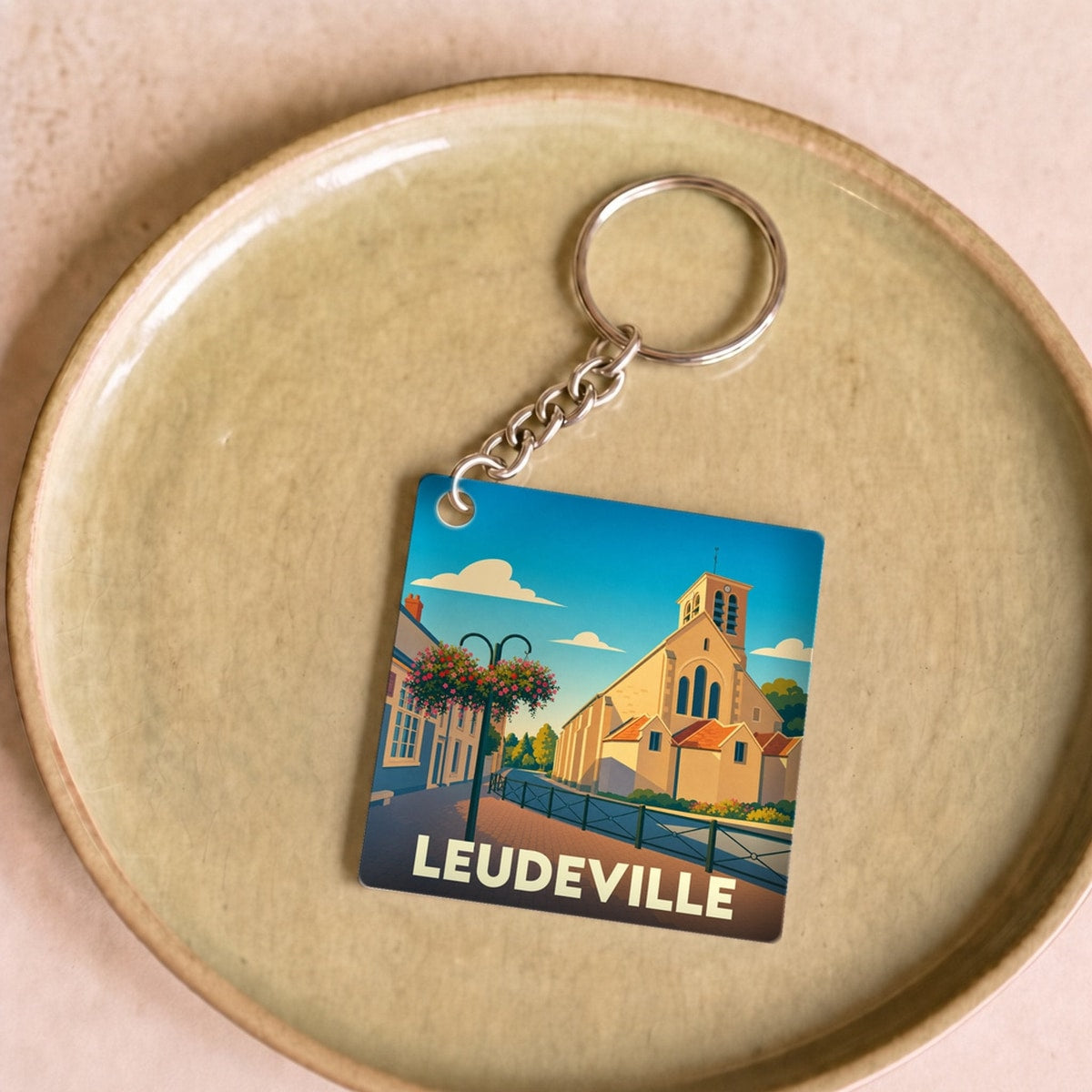 Porte-clés souvenir de la ville de Leudeville avec une illustration stylisée.