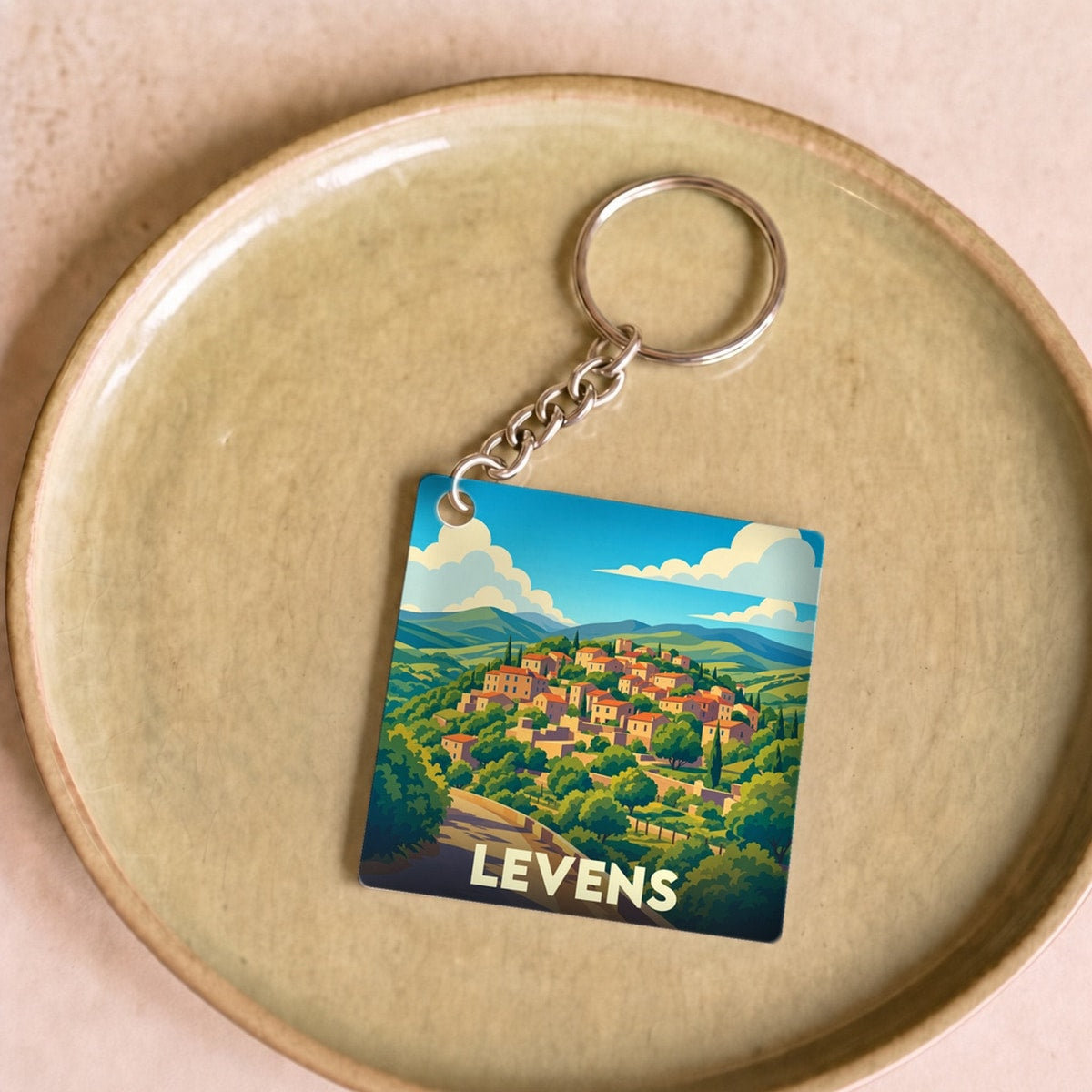 Porte-clés souvenir de la ville de Levens avec une illustration stylisée d'un village perché.
