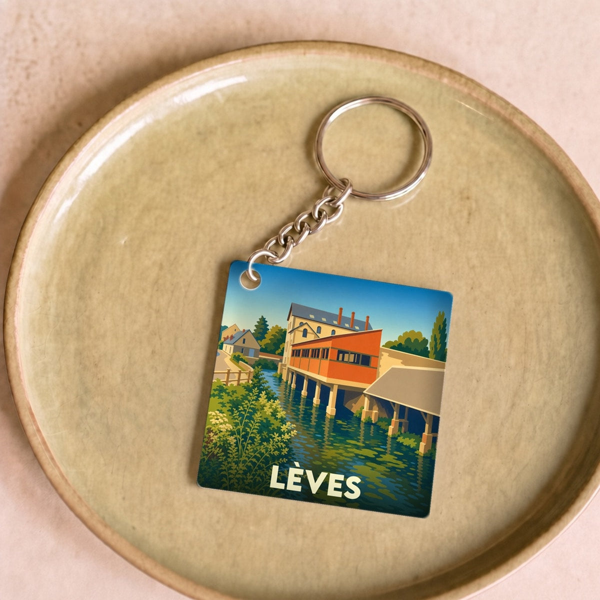 Porte-clés souvenir de la ville de Lèves avec une illustration stylisée d'un moulin au bord de l'eau.