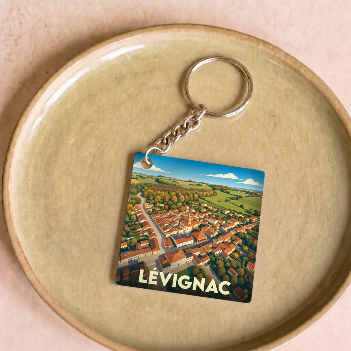 Porte-clés souvenir de la ville de Lévignac avec une illustration aérienne stylisée.
