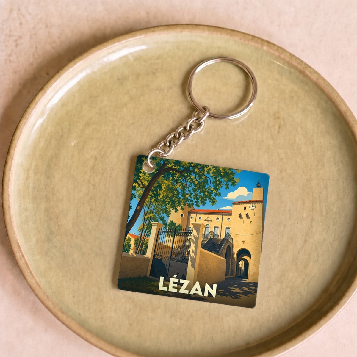Porte-clés souvenir de la ville de Lézan avec une illustration stylisée de son patrimoine architectural.
