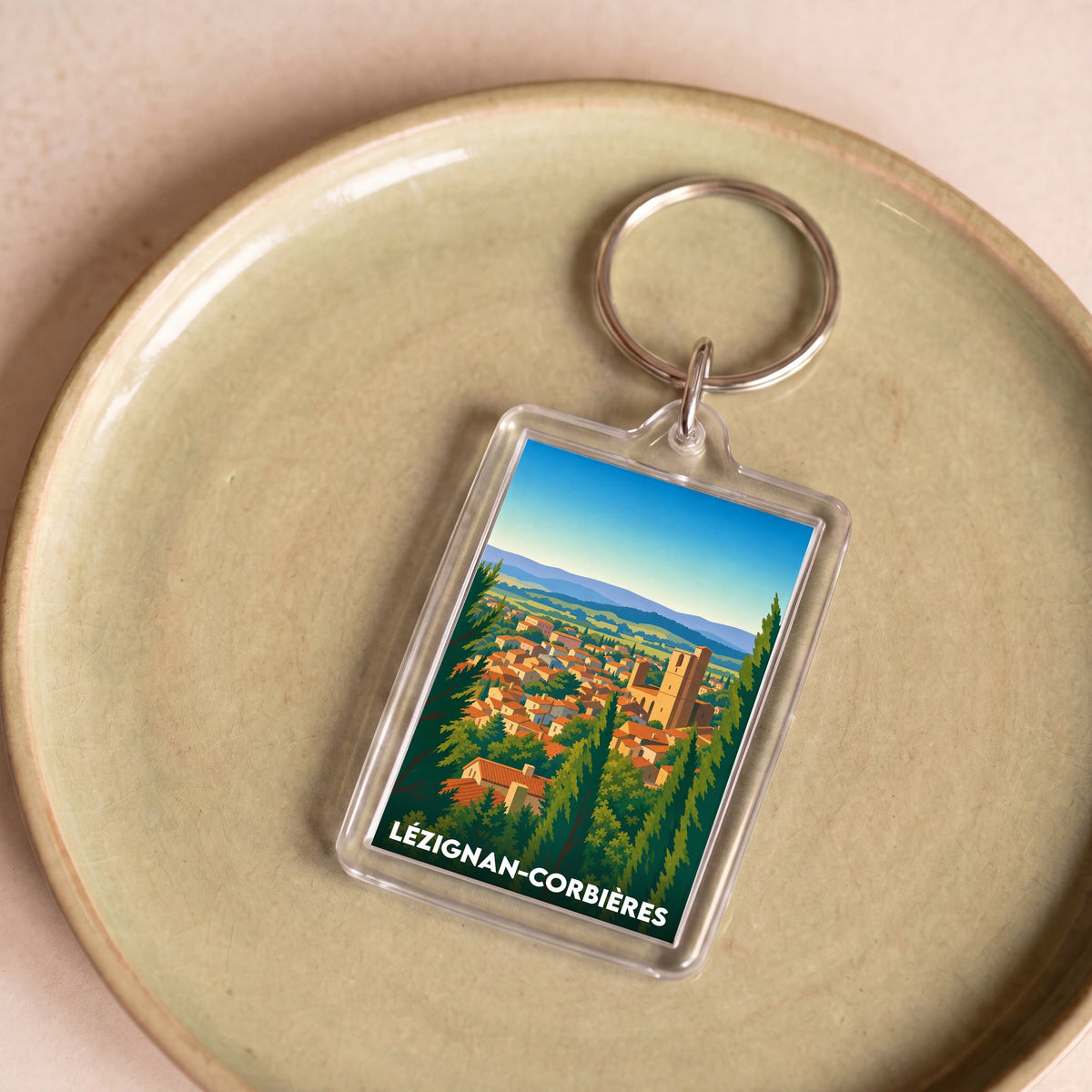 Porte-clés souvenir de la ville de Lézignan-Corbières avec une illustration stylisée.