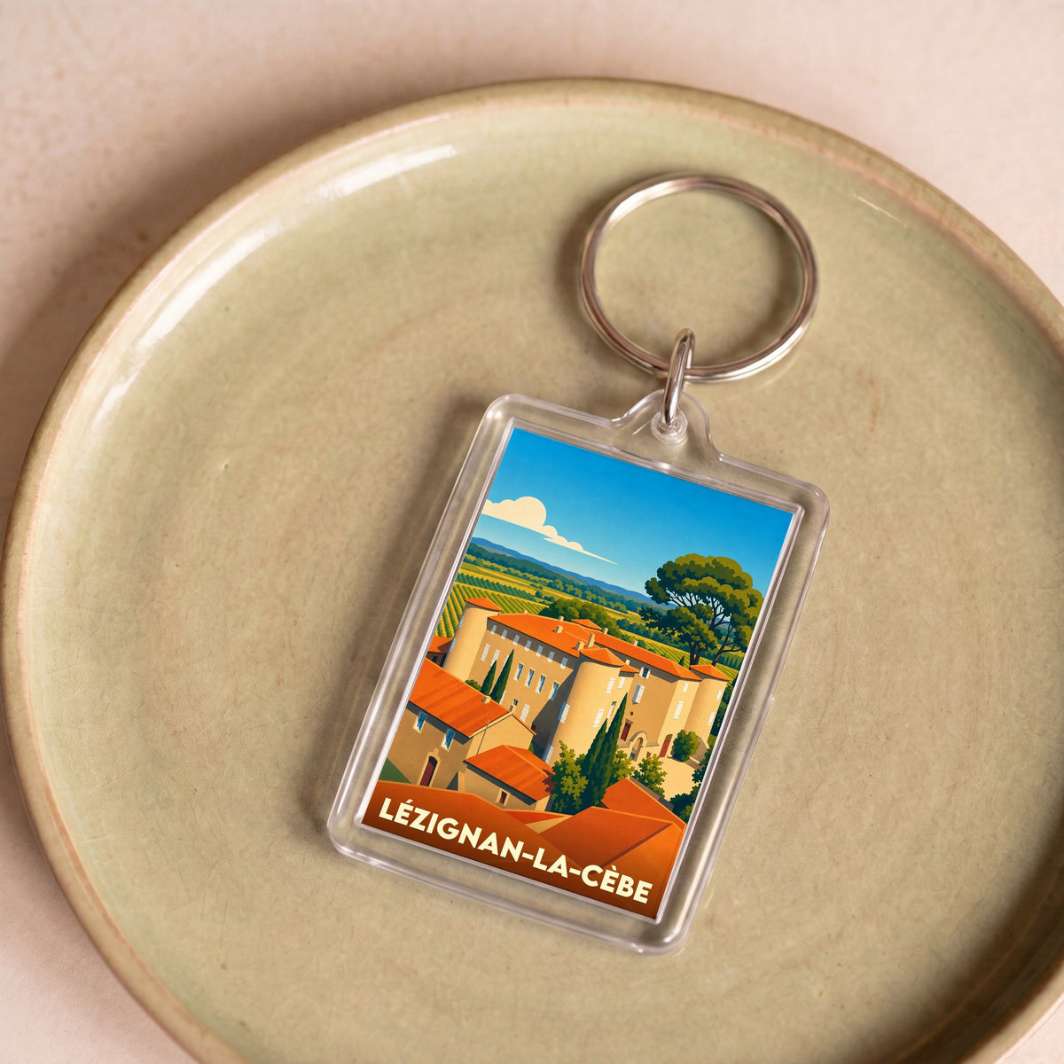 Porte-clés souvenir de la ville de Lézignan-la-Cèbe avec une illustration stylisée.