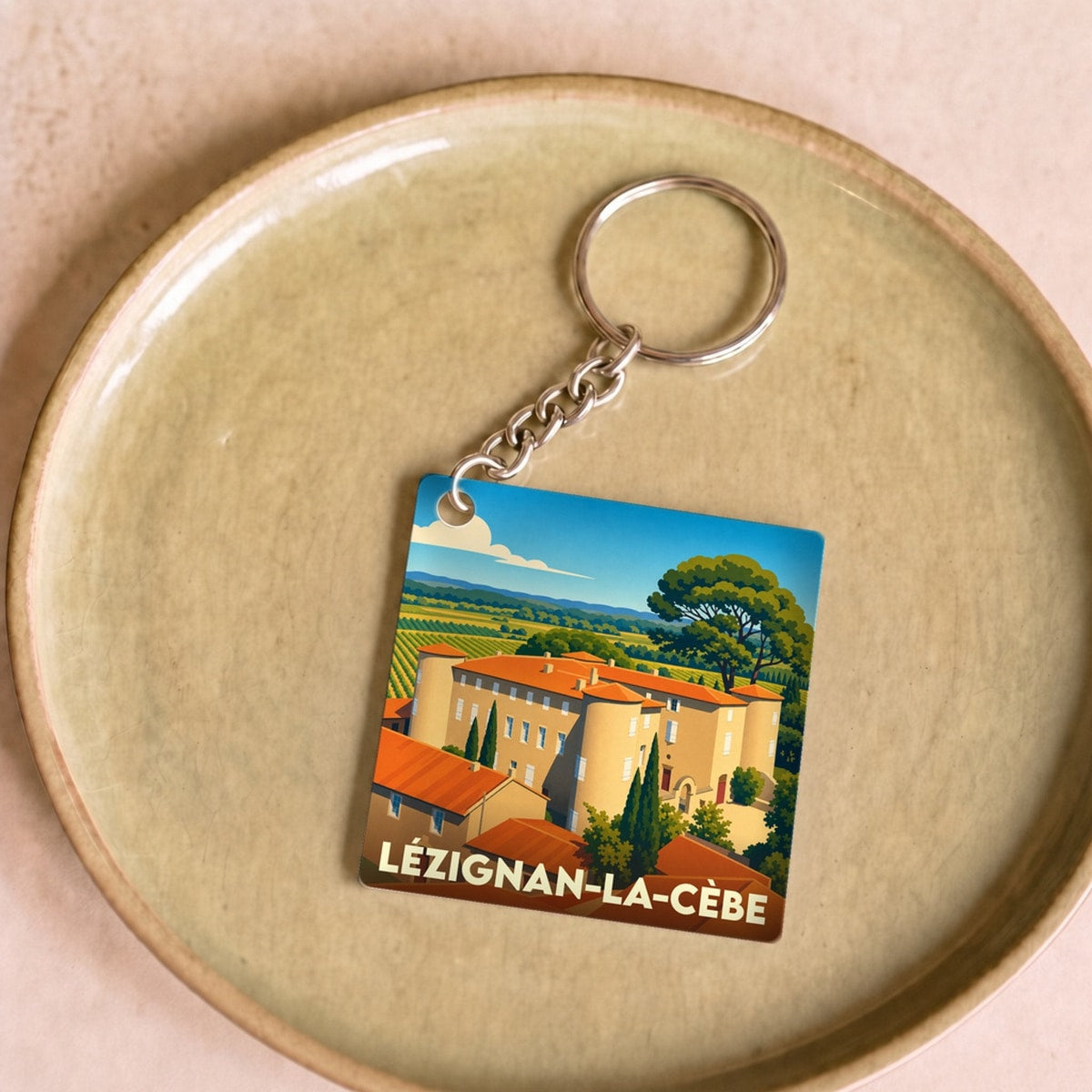 Porte-clés souvenir de la ville de Lézignan-la-Cèbe avec une illustration stylisée.