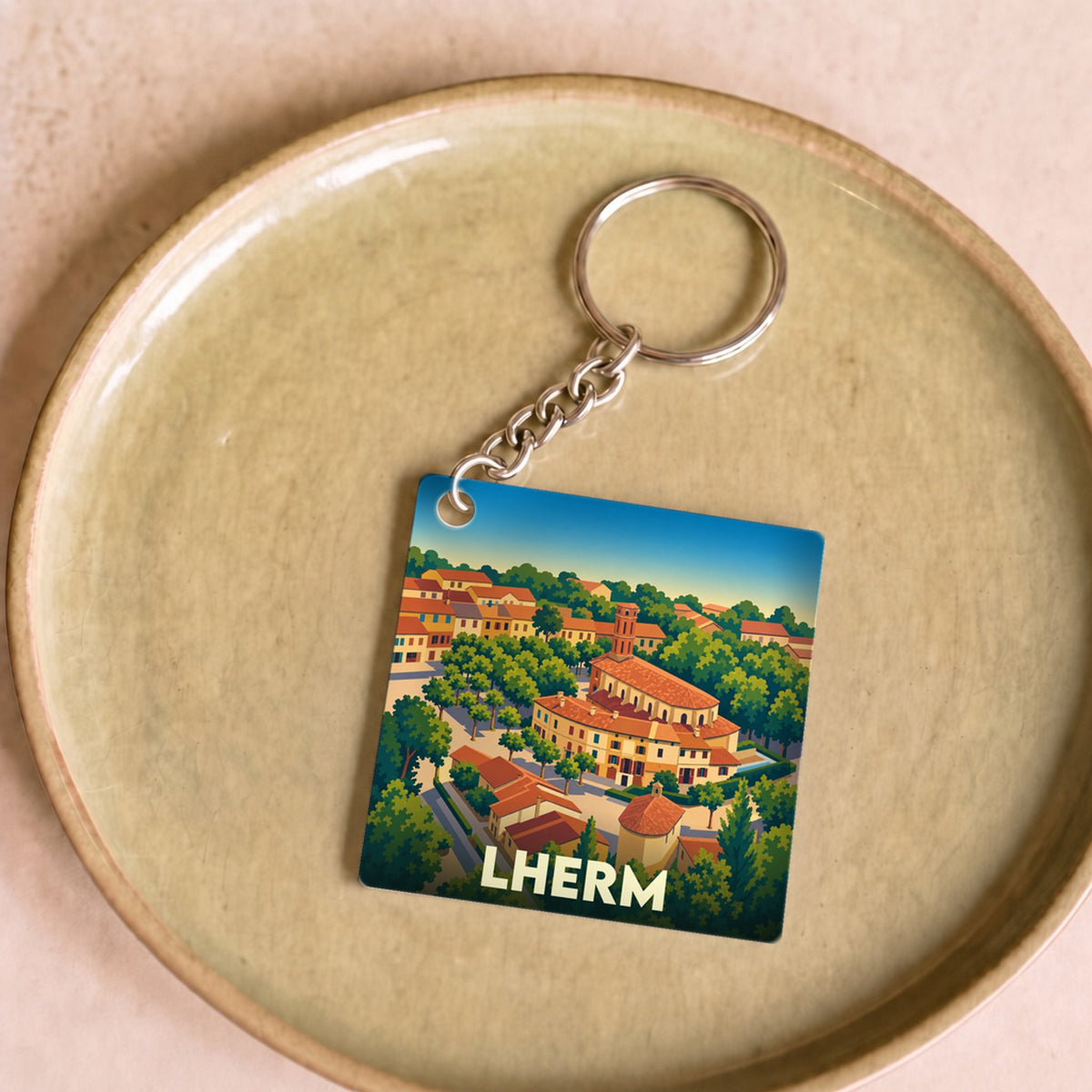 Porte-clés souvenir de la ville de Lherm avec une illustration stylisée.