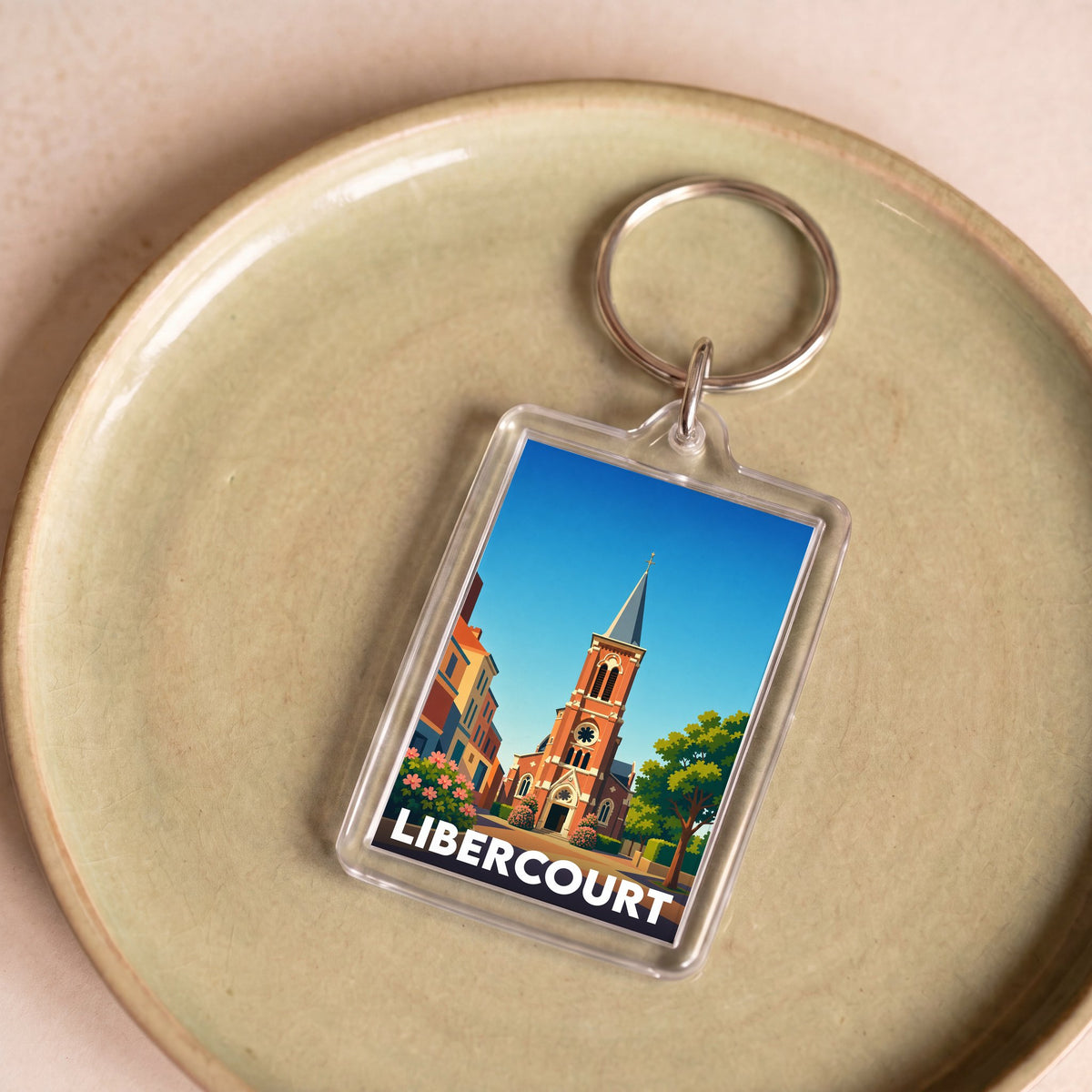 Porte-clés souvenir de la ville de Libercourt avec une illustration stylisée d'une église sous un ciel bleu.