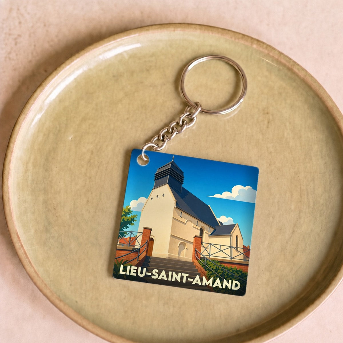 Porte-clés souvenir de la ville de Lieu-Saint-Amand avec une illustration stylisée de son église.
