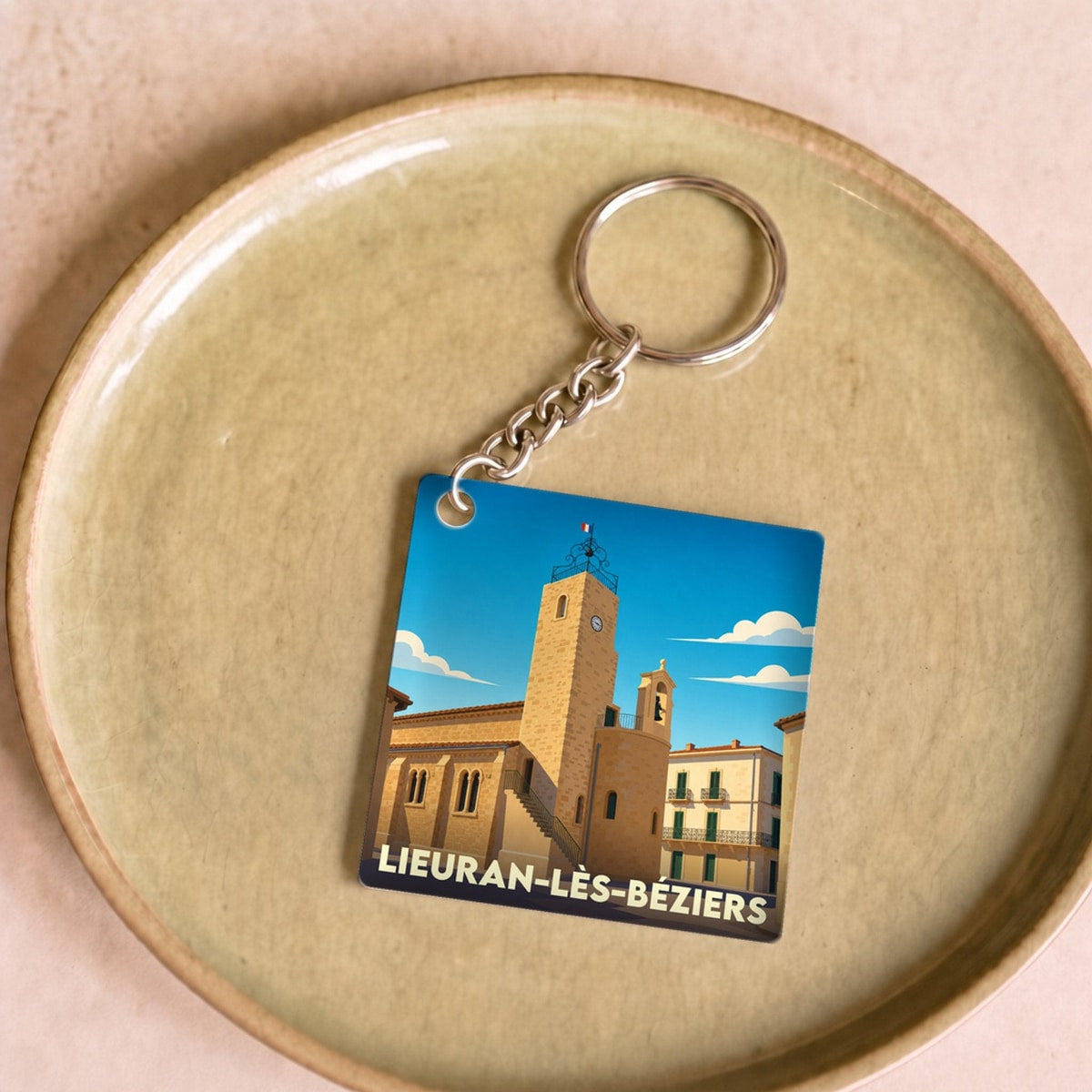 Porte-clés souvenir de la ville de Lieuran-lès-Béziers avec une illustration stylisée.