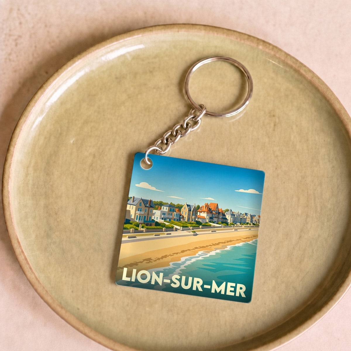 Porte-clés souvenir de la ville de Lion-sur-Mer avec une illustration stylisée de sa plage et de son front de mer.