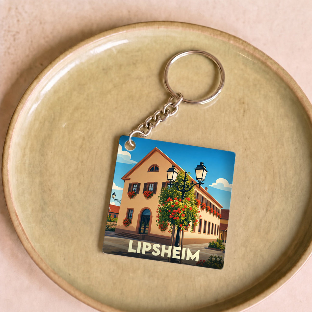 Porte-clés souvenir de la ville de Lipsheim avec une illustration stylisée d'un bâtiment fleuri.