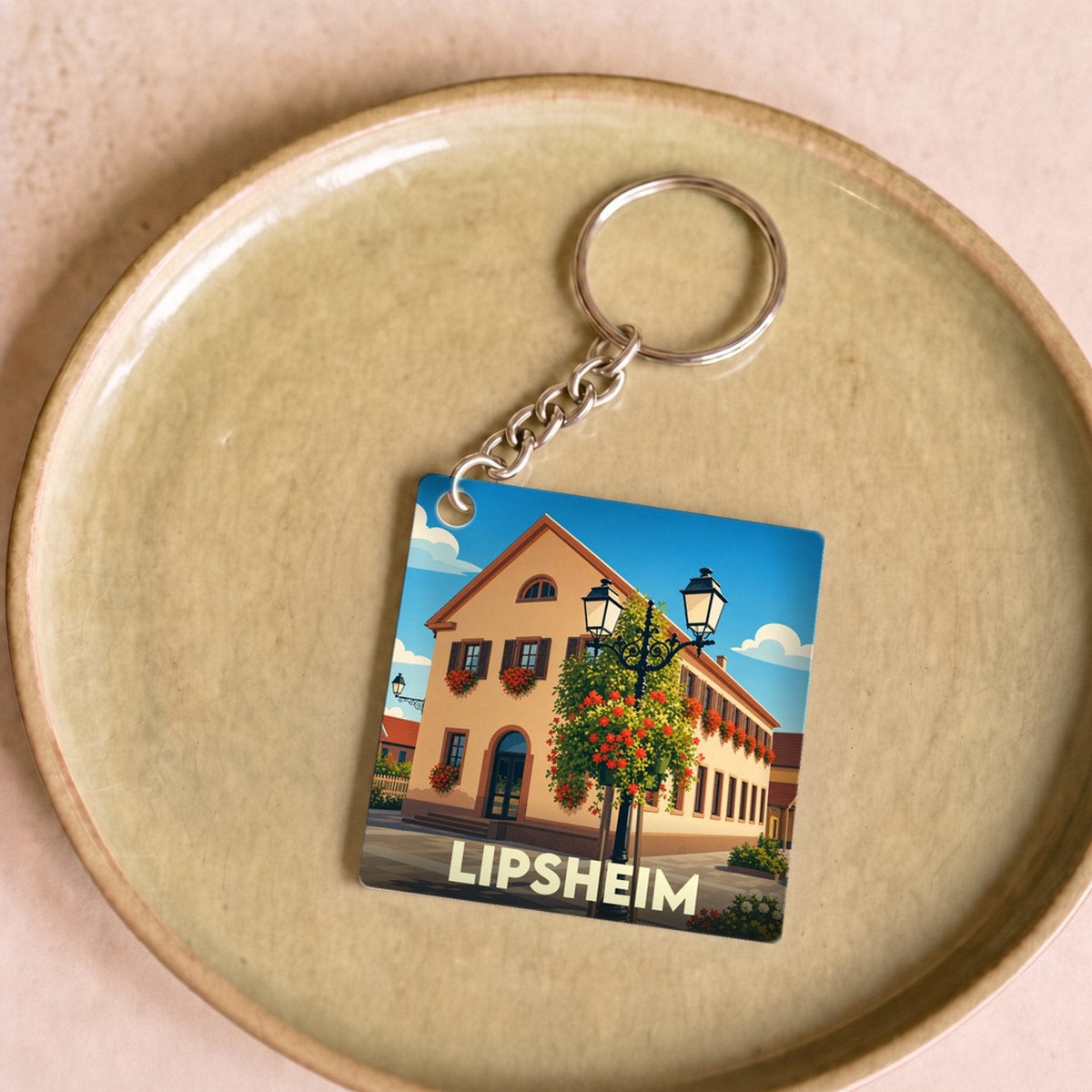 Porte-clés souvenir de la ville de Lipsheim avec une illustration stylisée d'un bâtiment fleuri.