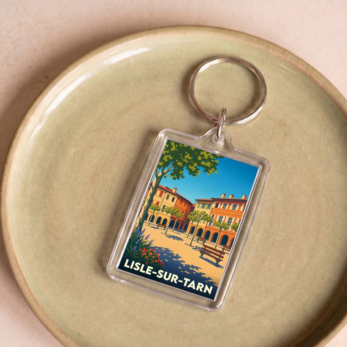 Porte-clés souvenir de la ville de Lisle-sur-Tarn avec une illustration stylisée de sa place principale.