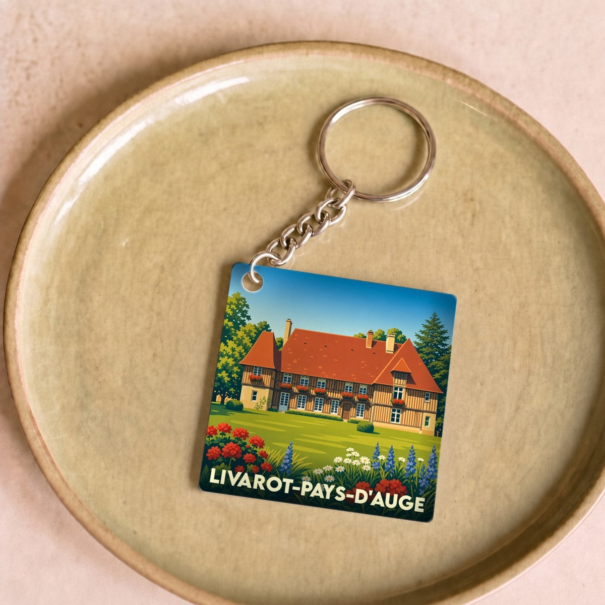 Porte-clés souvenir de la ville de Livarot-Pays-d'Auge avec une illustration stylisée d'un manoir normand.