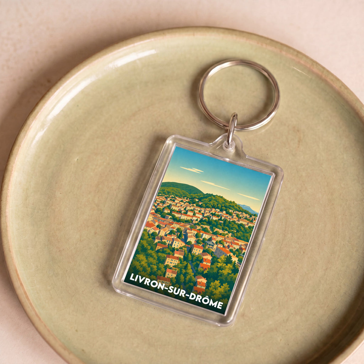Porte-clés souvenir de la ville de Livron-sur-Drôme avec une illustration panoramique stylisée.