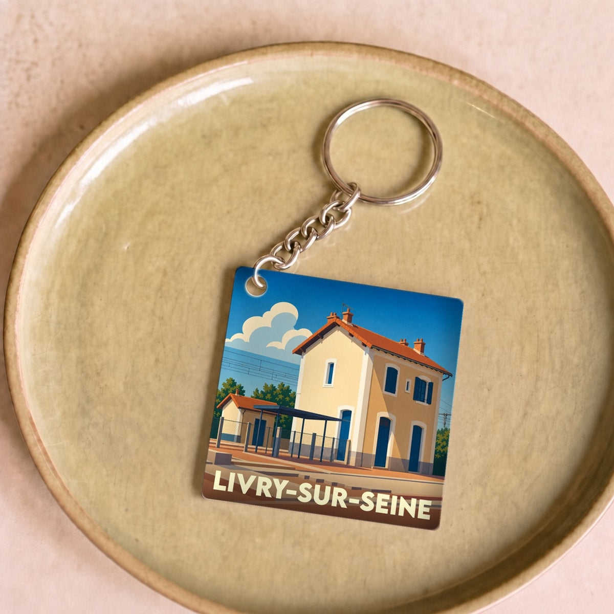 Porte-clés souvenir de la ville de Livry-sur-Seine avec une illustration stylisée de sa gare.