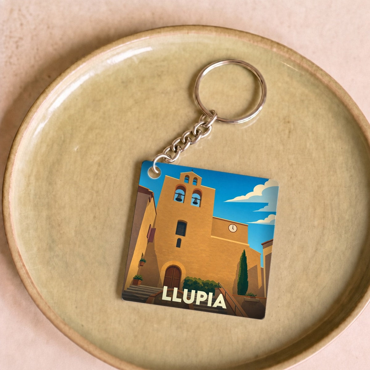 Porte-clés souvenir de la ville de Llupia avec une illustration stylisée de son église.