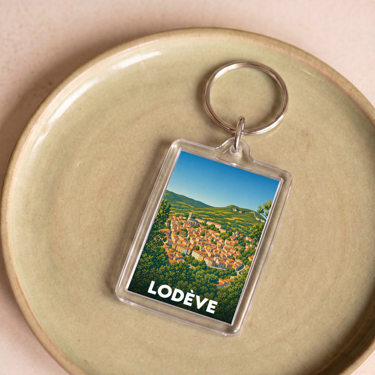Porte-clés souvenir de la ville de Lodève avec une illustration stylisée d'un paysage urbain.
