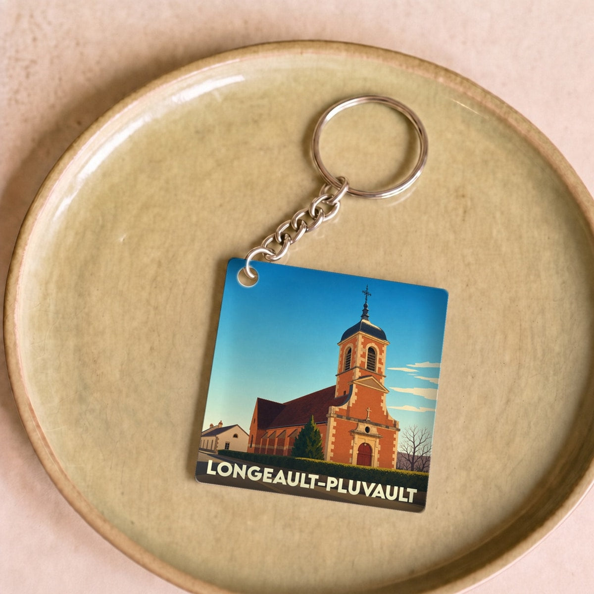 Porte-clés souvenir de la ville de Longeault-Pluvault avec une illustration stylisée de son église.