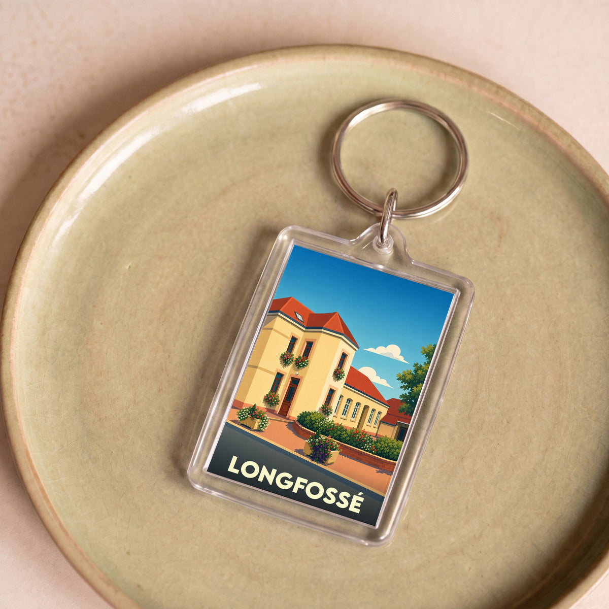 Porte-clés souvenir de la ville de Longfossé avec une illustration stylisée d'un bâtiment fleuri.