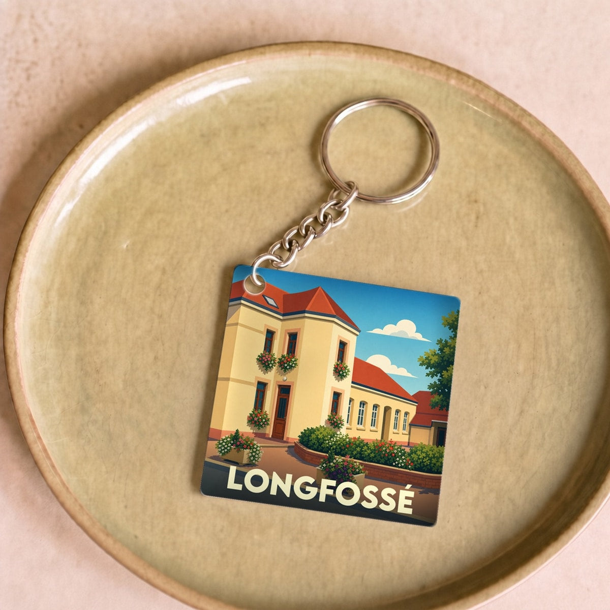 Porte-clés souvenir de la ville de Longfossé avec une illustration stylisée d'un bâtiment fleuri.