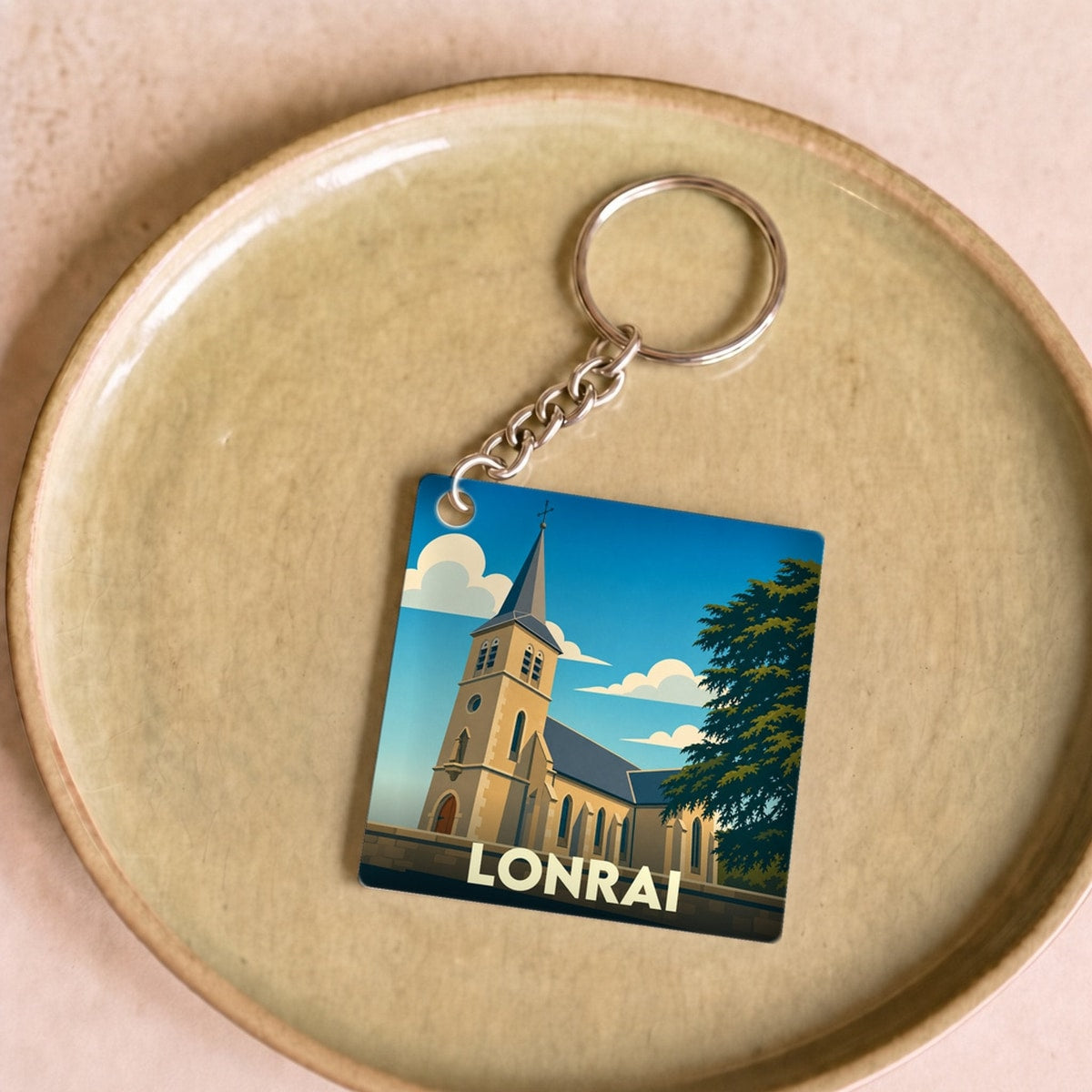 Porte-clés souvenir de la ville de Lonrai avec une illustration stylisée d'une église sous un ciel bleu.
