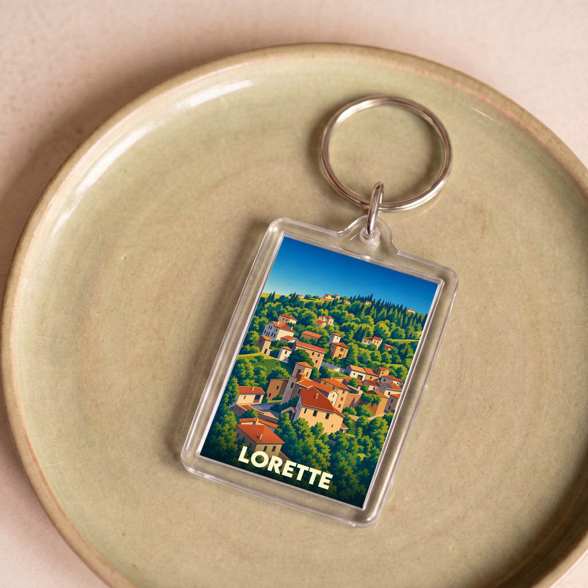 Porte-clés souvenir de la ville de Lorette avec une illustration stylisée de son paysage vallonné.