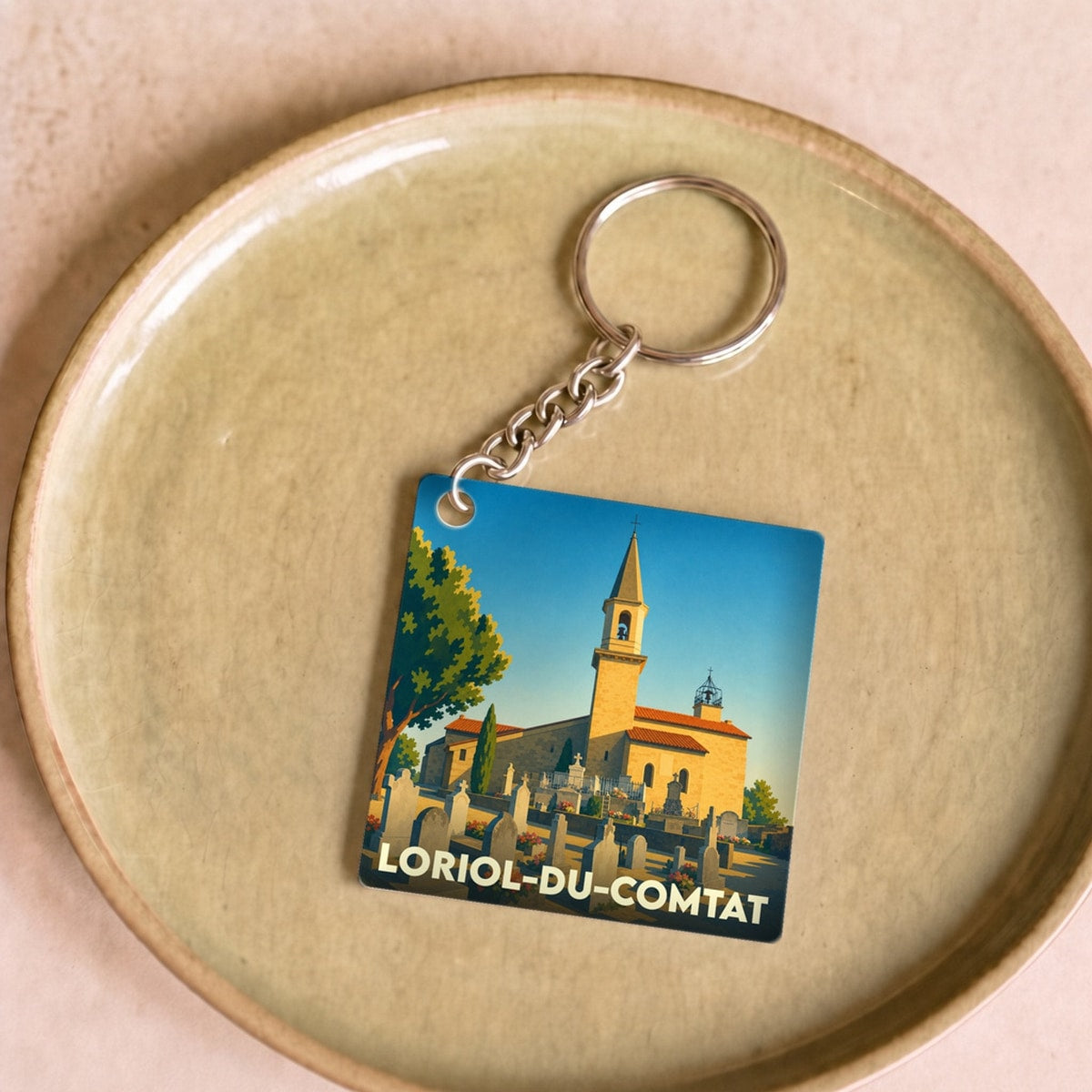 Porte-clés souvenir de la ville de Loriol-du-Comtat avec une illustration stylisée de son église et de son cimetière.