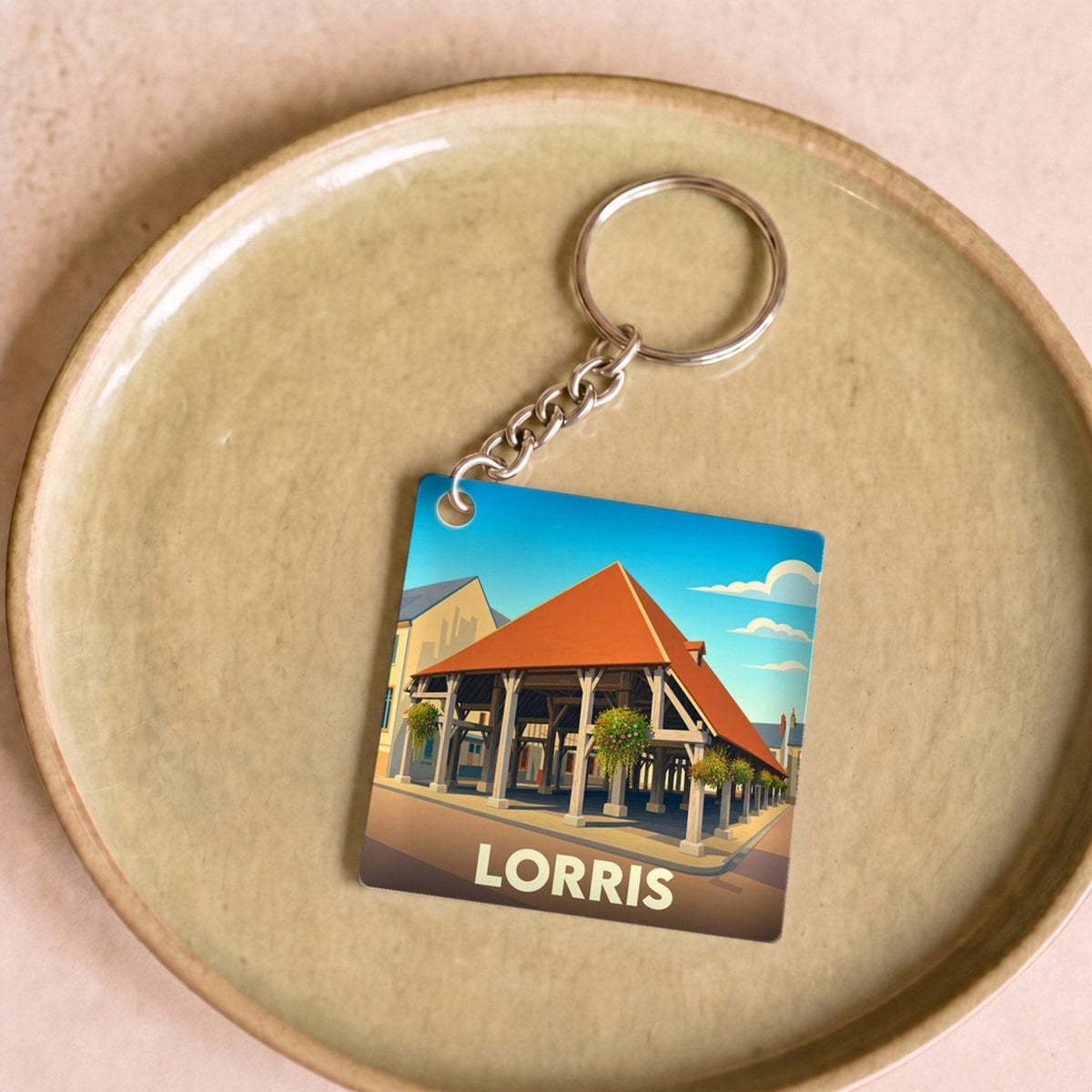 Porte-clés souvenir de la ville de Lorris avec une illustration stylisée de ses halles historiques.