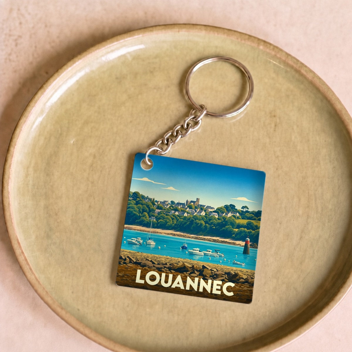 Porte-clés souvenir de la ville de Louannec avec une illustration stylisée du bord de mer.
