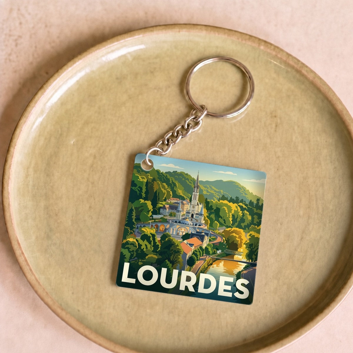 Porte-clés souvenir de la ville de Lourdes avec une illustration stylisée de son sanctuaire.