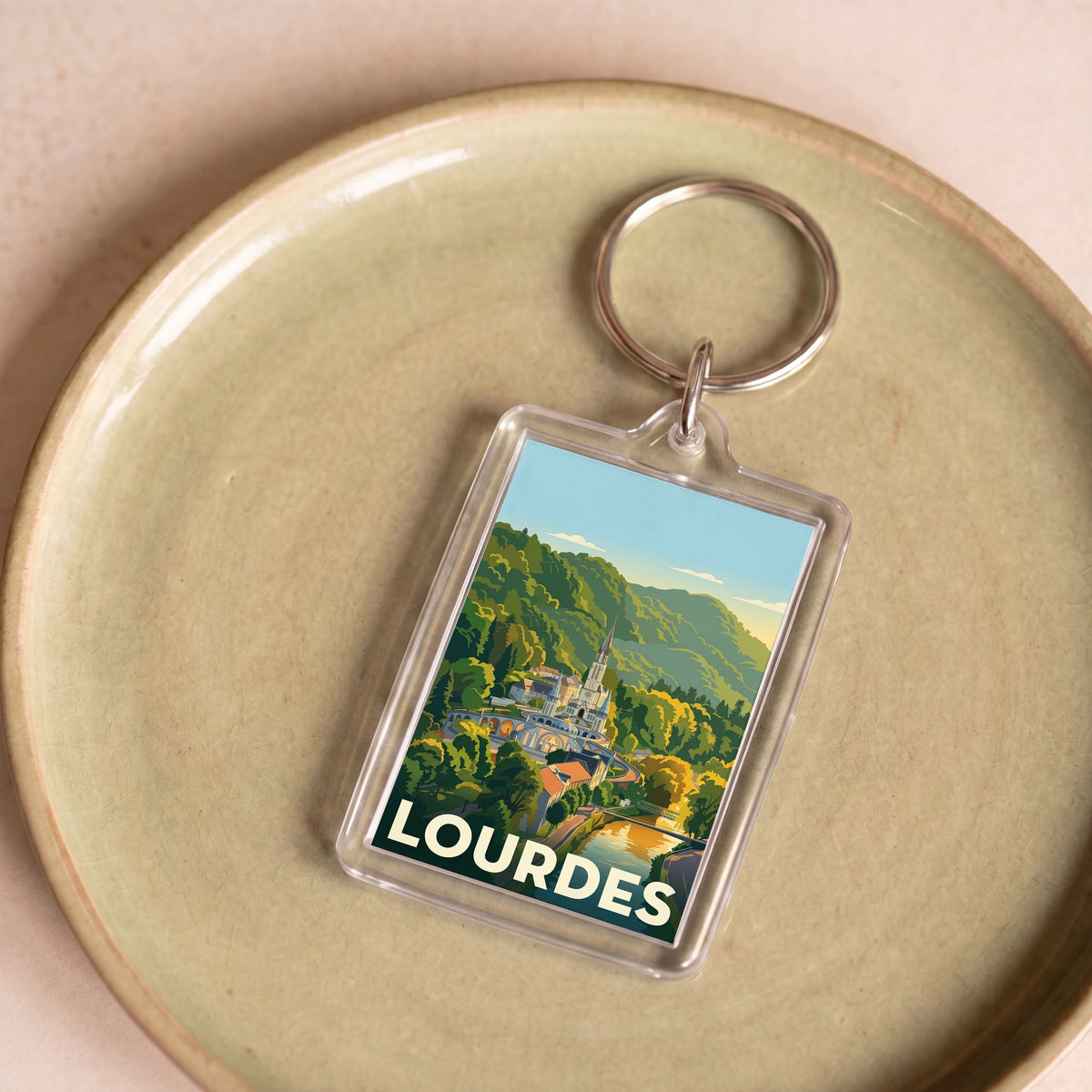 Porte-clés souvenir de la ville de Lourdes avec une illustration stylisée de son sanctuaire.