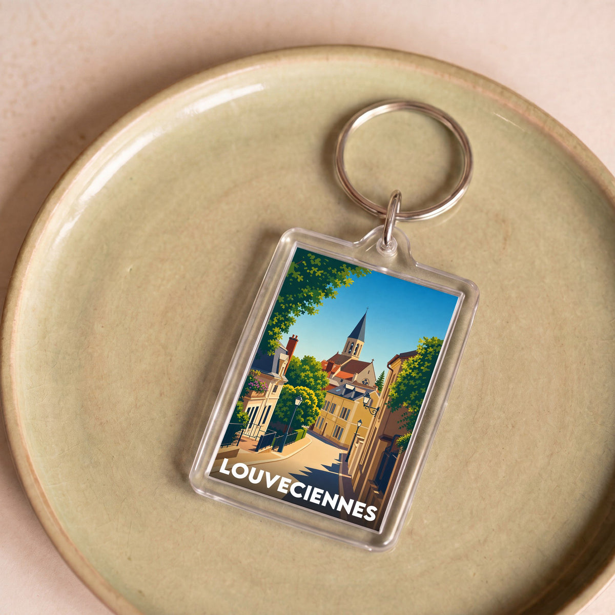 Porte-clés souvenir de la ville de Louveciennes avec une illustration stylisée.