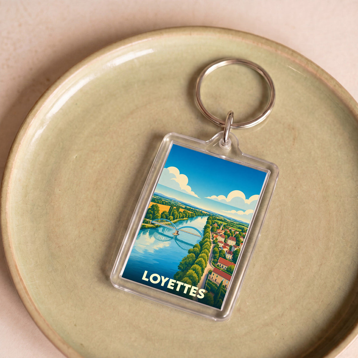 Porte-clés souvenir de la ville de Loyettes avec une illustration stylisée d'un pont enjambant une rivière.