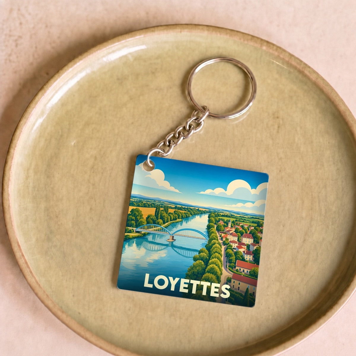 Porte-clés souvenir de la ville de Loyettes avec une illustration stylisée d'un pont enjambant une rivière.