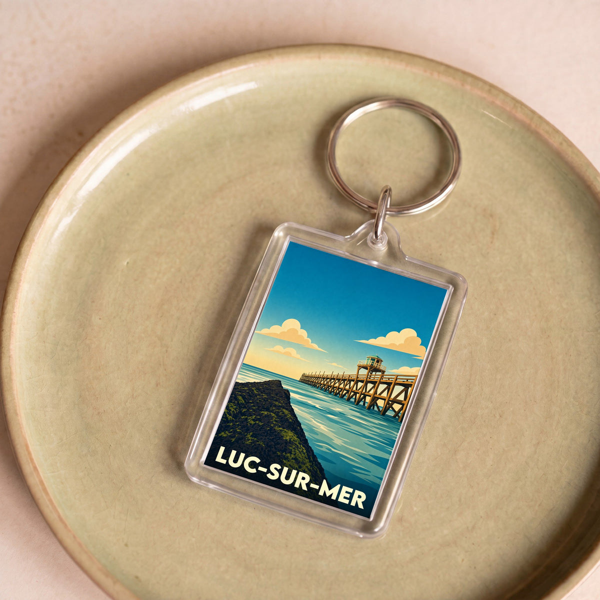 Porte-clés souvenir de la ville de Luc-sur-Mer avec une illustration stylisée de sa jetée en bois.
