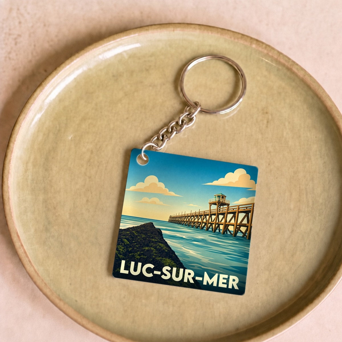 Porte-clés souvenir de la ville de Luc-sur-Mer avec une illustration stylisée de sa jetée en bois.