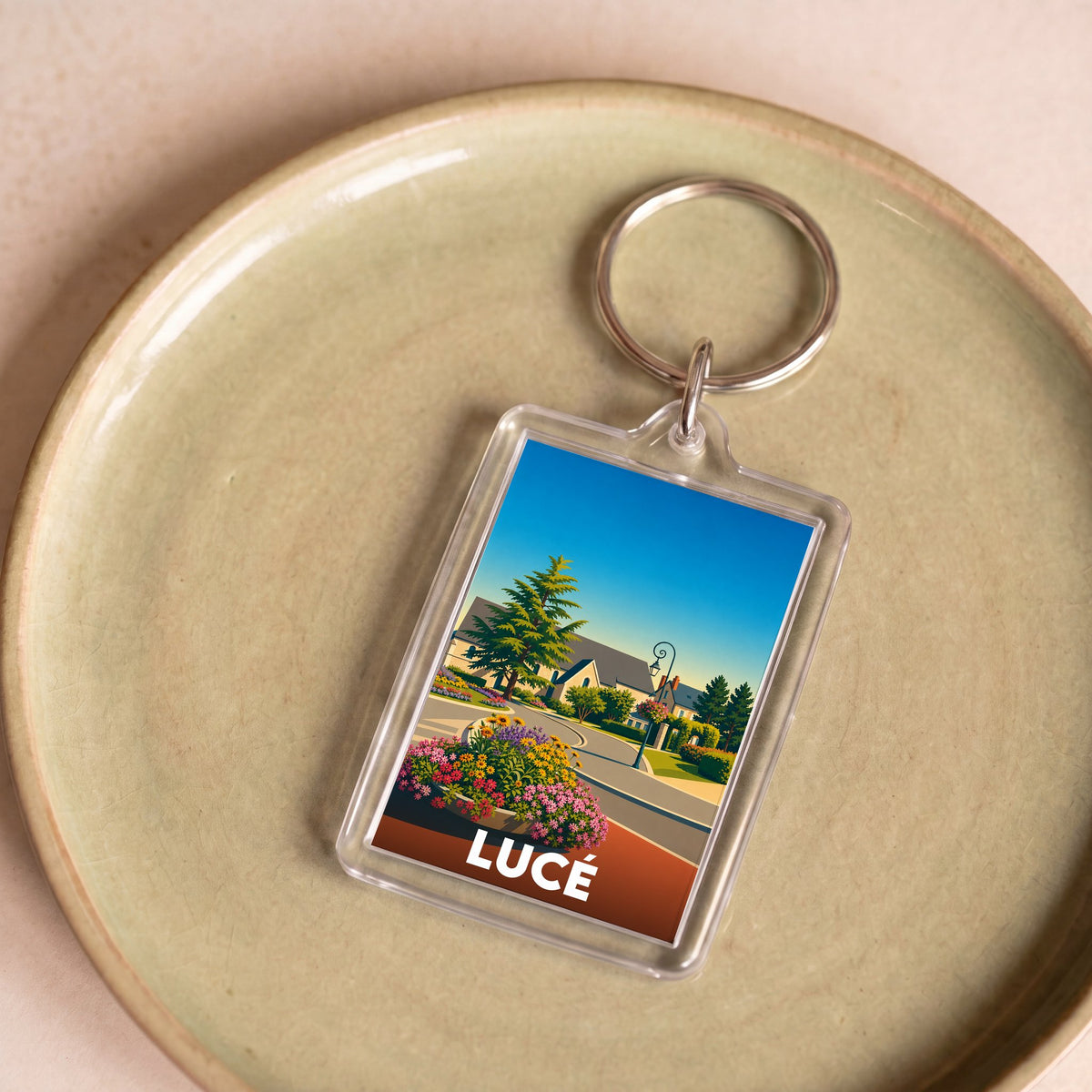 Porte-clés souvenir de la ville de Lucé avec une illustration stylisée et colorée de son paysage.