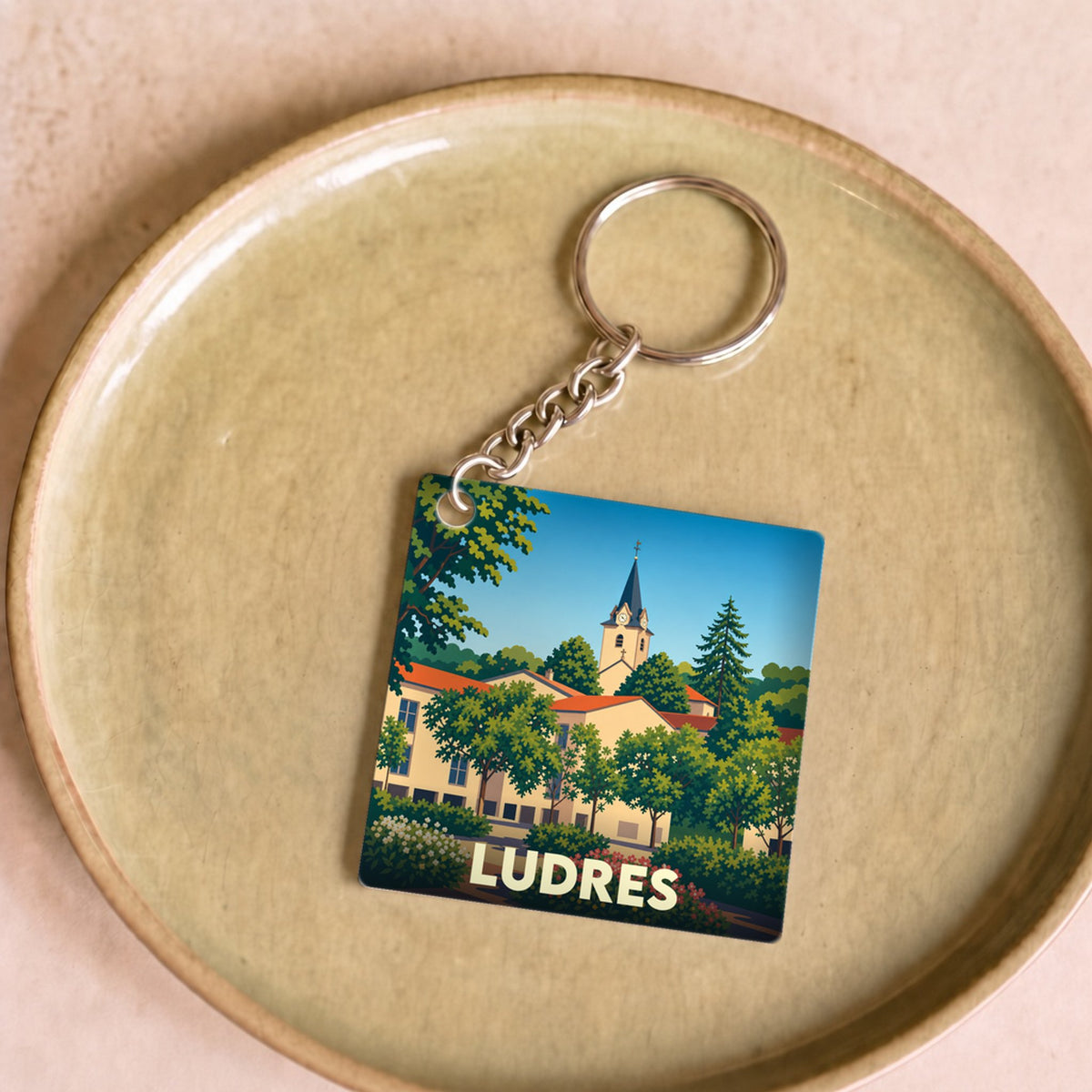 Porte-clés souvenir de la ville de Ludres avec une illustration stylisée.