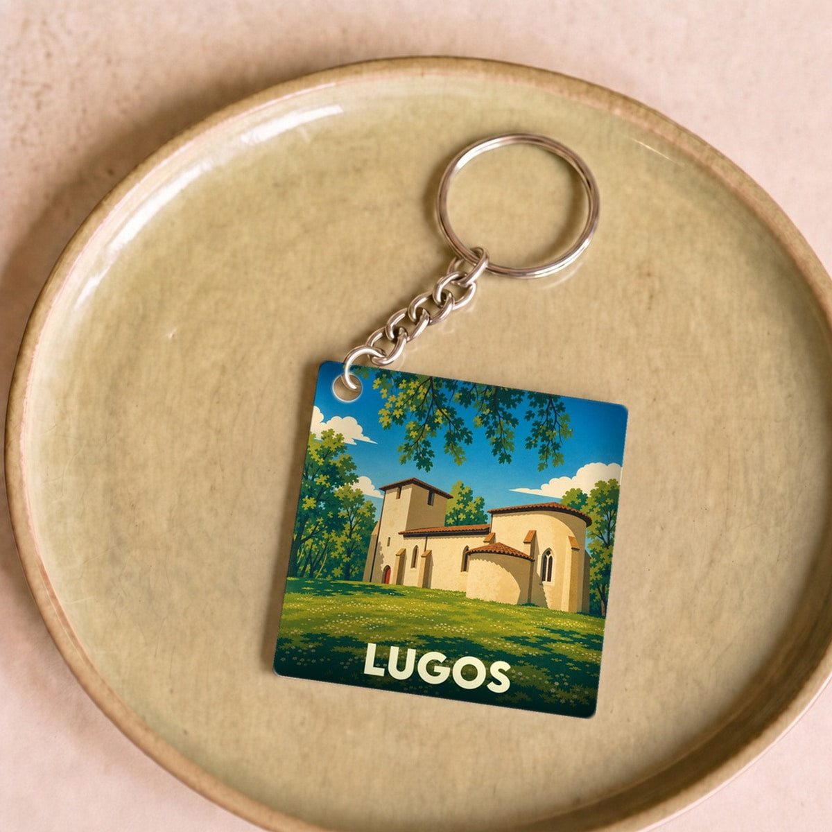 Porte-clés souvenir de la ville de Lugos avec une illustration stylisée de son église dans un paysage verdoyant.